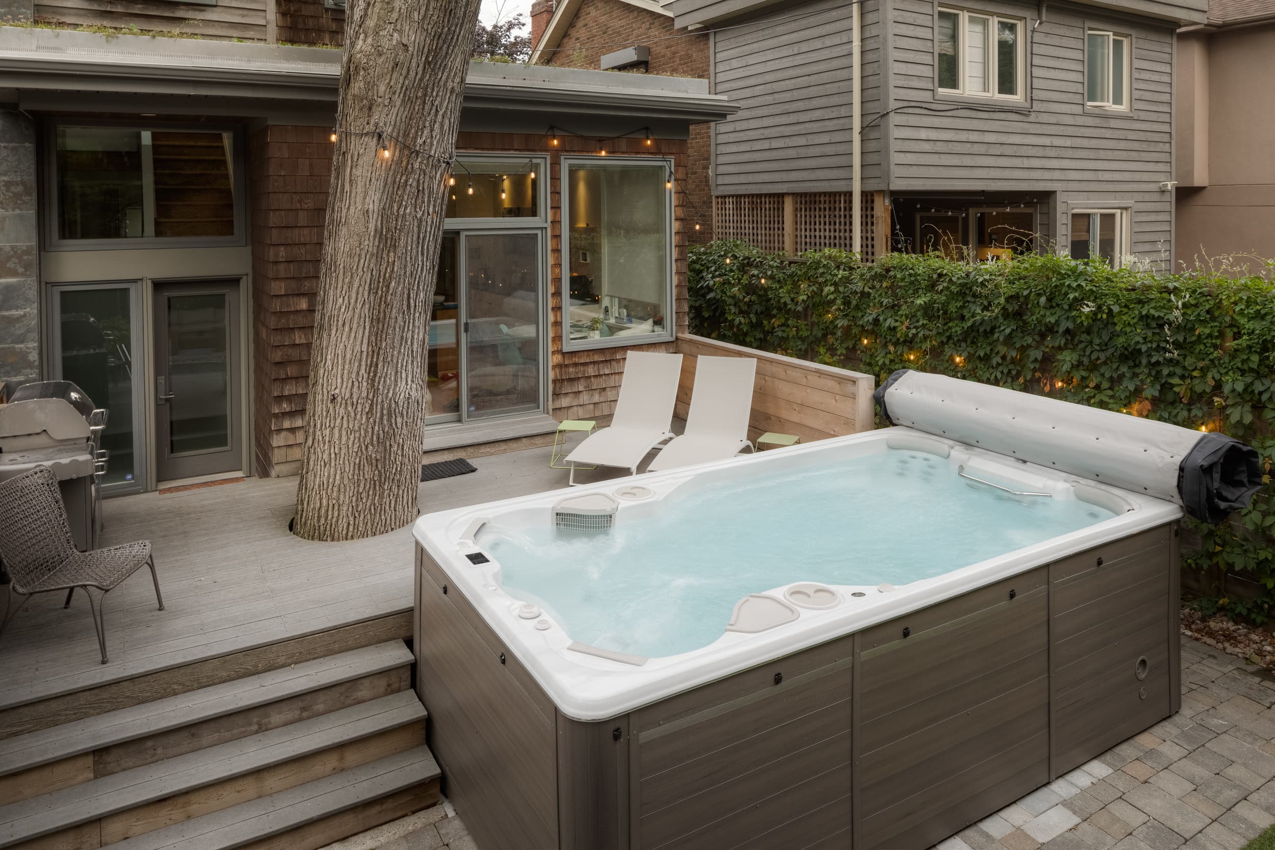Hydropool swim spa on a Toronto backyard patio with string lights at dusk